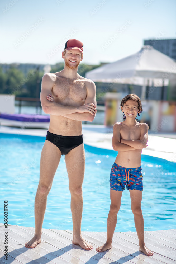 Man and boy in swimming suits near pool Man and boy in swimming suits near pool