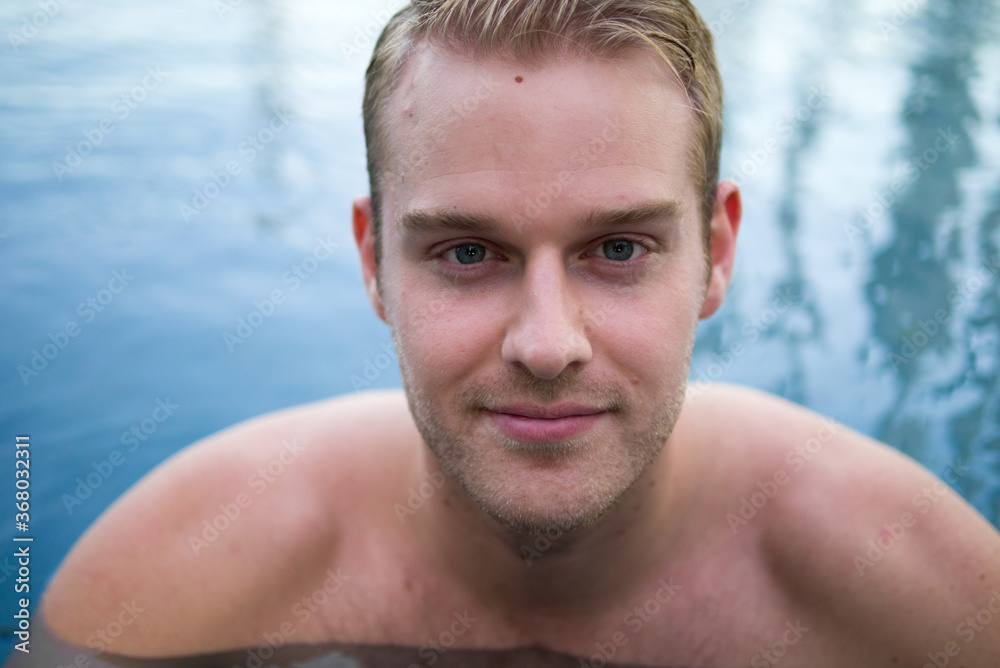 Obraz premium Young handsome shirtless man with blond hair in the swimming pool