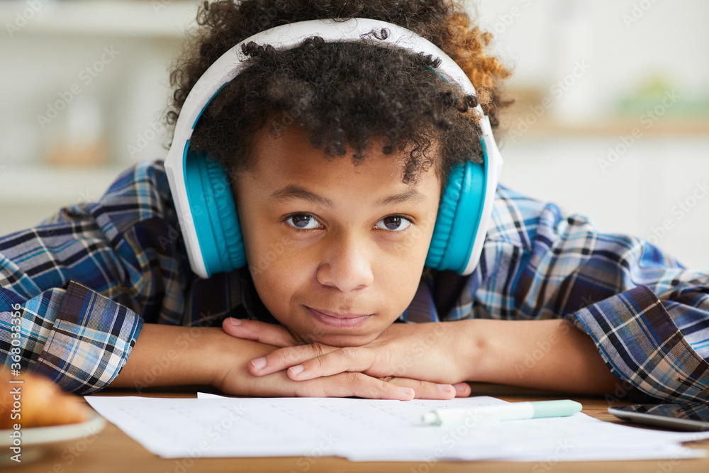Φωτογραφία Close-up of African schoolboy with curly hair in headphones looking at camera wh