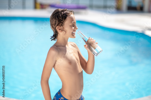 Smiling boy with closed eyes with bottle of water