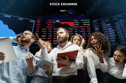 Intense. Nervous tensioned investors analyzing crisis stock market with charts of falling stock exchange. Defaulted, crisis of exchange markets and funds. Overly concerned people with gadgets, papers.