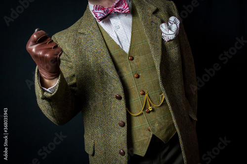 Portrait of Elegant Man in Vintage Tweed Suit and Leather Gloves. Retro Sartorial Style. Copy Space for Fashion. Vintage Attire. Concept of Classic and Eccentric British Gentleman. 