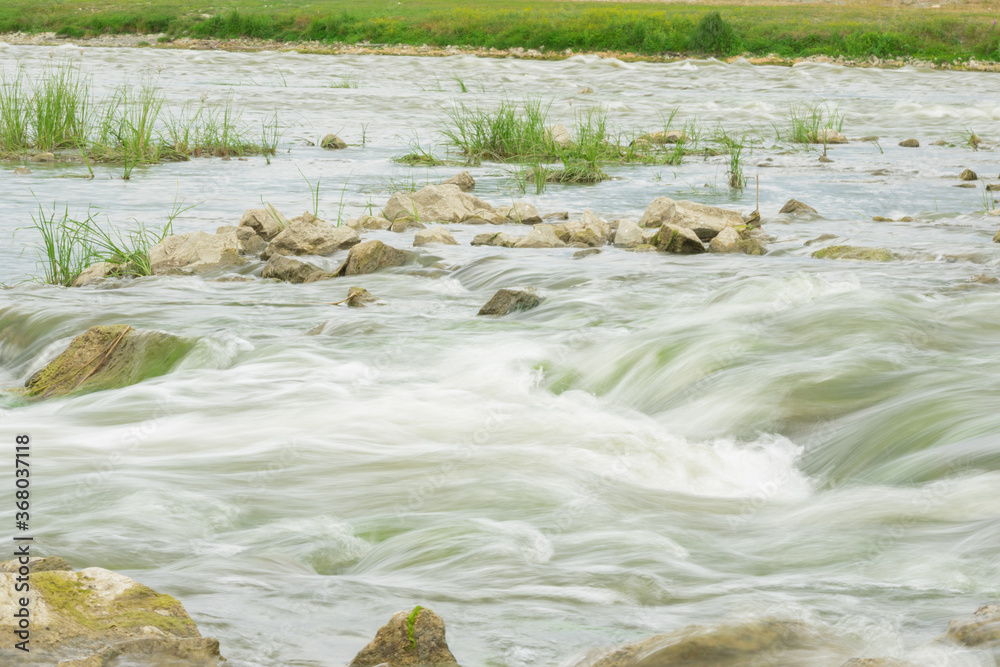 The flow of the river in the summer forest. Stones washed by water. Reflection on the water. water movement for a long exposure. The flow of the river in the summer forest. Stones washed by water. Reflection on the water. water movement for a long exposure.