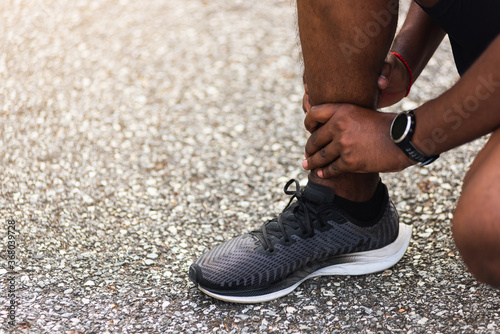 Close up Asian young sport runner black man wear watch hands joint hold leg pain because of twisted ankle broken while running at the outdoor street health park  healthy exercise Injury from workout