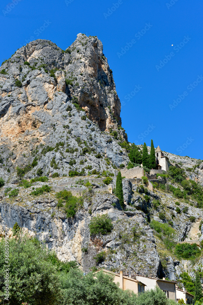 Moustiers-Sainte-Marie and Notre-Dame-de-Beavoir chapel in the mountain. Moustiers-Sainte-Marie is a commune in the Alpes-de-Haute-Provence department in southeastern France Moustiers-Sainte-Marie and Notre-Dame-de-Beavoir chapel in the mountain. Moustiers-Sainte-Marie is a commune in the Alpes-de-Haute-Provence department in southeastern France