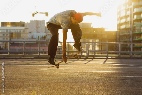 Obraz na plátně Skateboarder doing a trick at the city's street in summer's sunshine