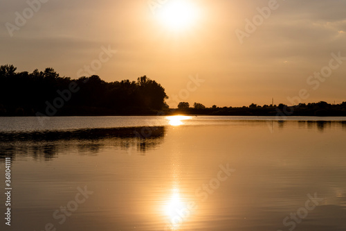Scenic view of Sunset above the lake. Sun reflecting out of water surface. Landscape photo