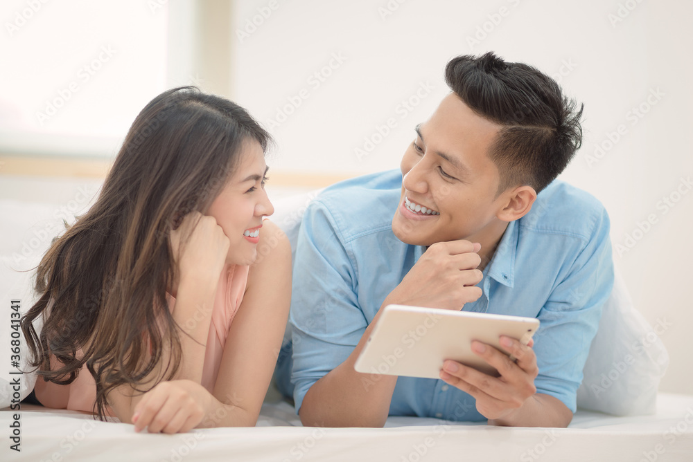 Asian couple lovers enjoy using smart tablet for shopping online together in bedroom. Couple lover happiness,family and valentine concept. Asian couple lovers enjoy using smart tablet for shopping online together in bedroom. Couple lover happiness,family and valentine concept.