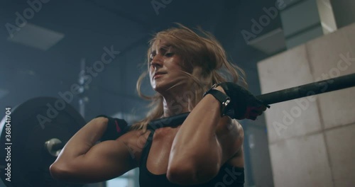 the woman athlete trains in the gym, raises the bar. Strength is power. Muscular female shirtless athlete doing deadlift exercise at the gym.