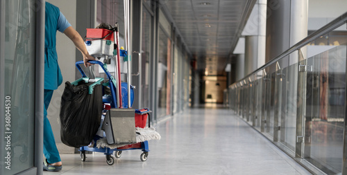 An employee pulls a trolley for cleaning offices. Woman cleaner is engaged in work. photo