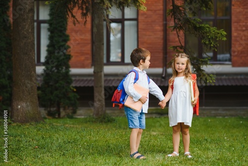 Happy children go back to school. Pupil of primary school go study with backpack outdoors. Kids go hand in hand. Beginning of lessons. First day of fall. Boy and girl from elementary student.