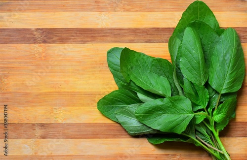 Fresh harvested tender green spinach placed on a wooden board. top view.