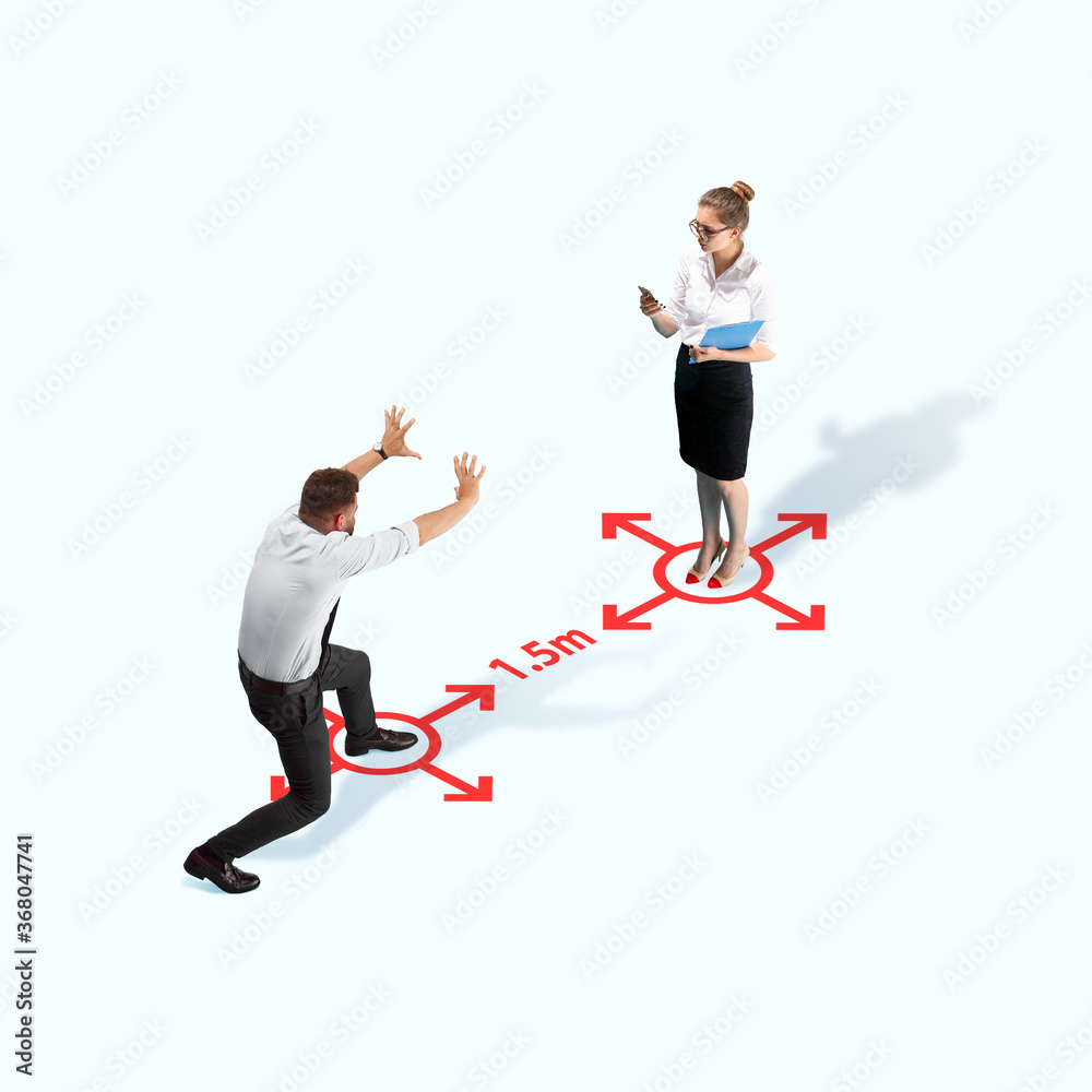 Studio shot of people demonstrating social distancing with arrows indicating the separation. Office workers during coronavirus outbreak with new rules for safety and healthcare. High angle view