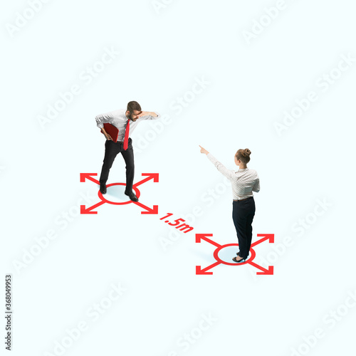 Studio shot of people demonstrating social distancing with arrows indicating the separation. Office workers during coronavirus outbreak with new rules for safety and healthcare. High angle view