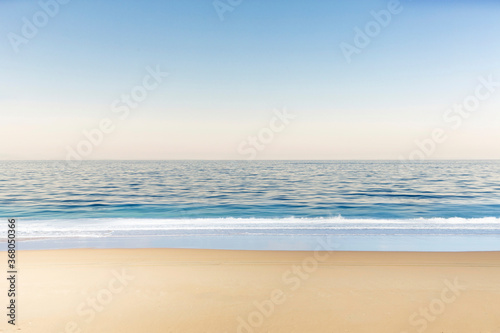 Soft wave of blue ocean on the sandy beach and soft blue sky with copy space for text