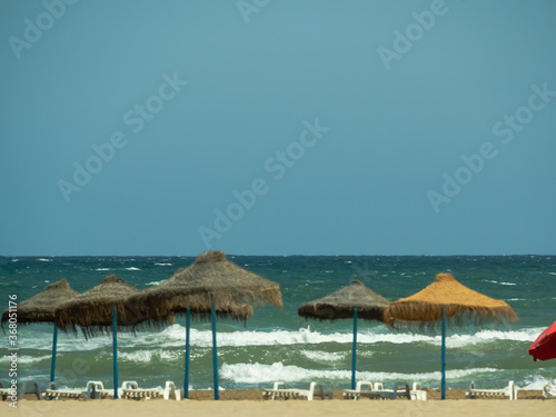 Sea waves blue sky and beach umbrellas
