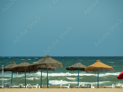 Sea waves blue sky and beach umbrellas