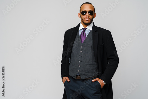 Photography studio shot of a african-american businessman wearing coat over light grey backg