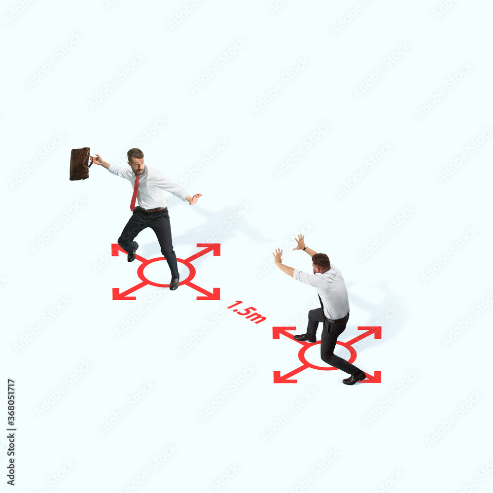 Studio shot of people demonstrating social distancing with arrows indicating the separation. Office workers during coronavirus outbreak with new rules for safety and healthcare. High angle view Studio shot of people demonstrating social distancing with arrows indicating the separation. Office workers during coronavirus outbreak with new rules for safety and healthcare. High angle view