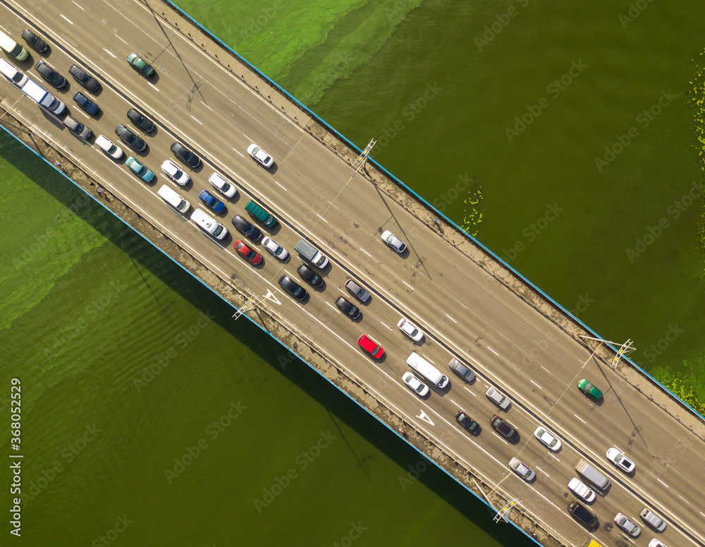 Cars travel along the North Bridge over the Dnieper River in Kiev. Summer sunny day, green algae bloom in the water.