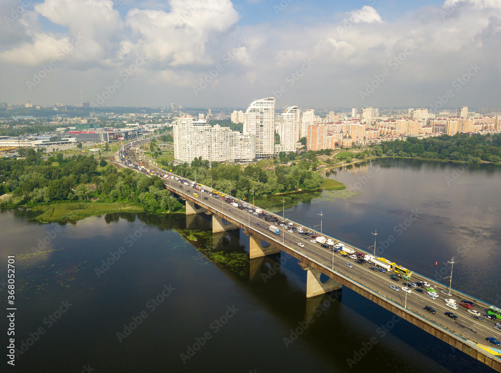 Aerial drone view. Cars travel along the North Bridge over the Dnieper River in Kiev. Summer sunny day.