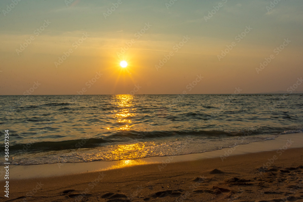 Colorful sea beach sunrise with deep blue sky and sun rays.