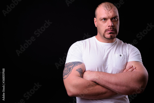 Portrait of muscular bald bearded man with arms crossed