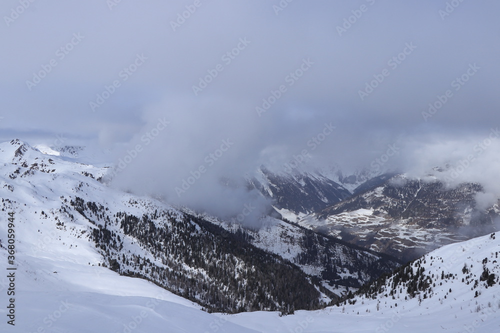 View of the snowy Villgratental valley between Austria Alps in Tyrol in western Austria. The peaks of these 2,000-meter mountains are lost in fog and thick clouds. Ski resort Sillian