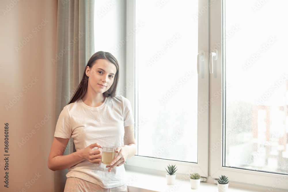 Beautiful woman drinking morning tea behind window