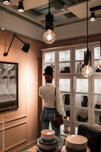 Anonymous black customer choosing dishware in store during coronavirus pandemic