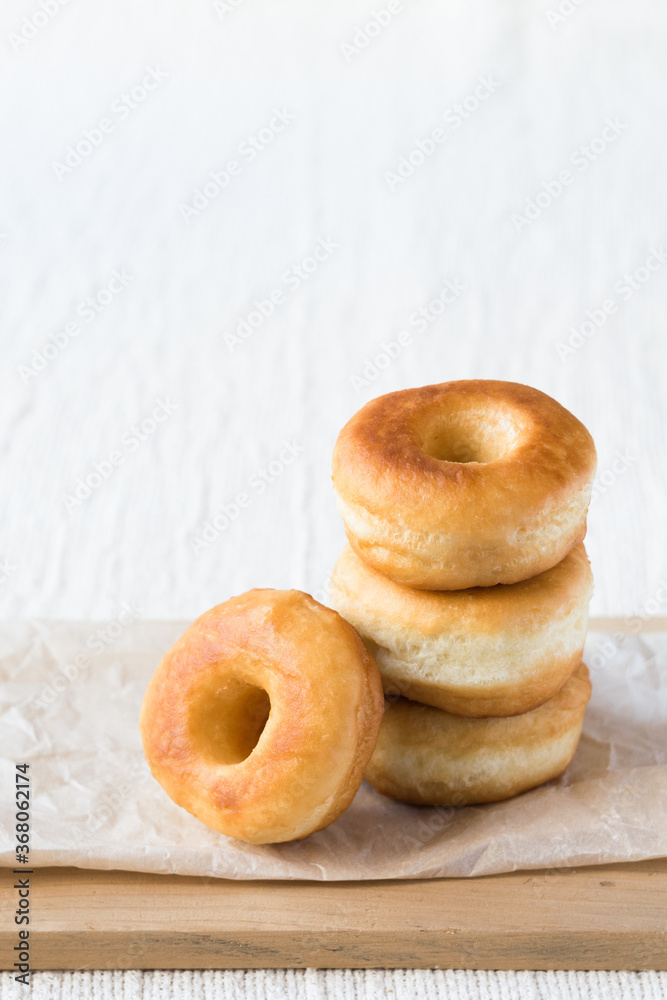 Donuts on a paper on light rustic textile background, vertical orientation, copy space