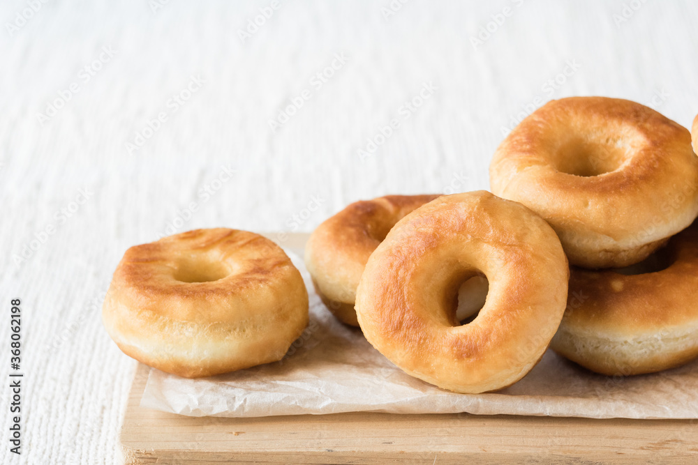 Donuts on a paper on light rustic textile background, horizontal orientation, selective focus Donuts on a paper on light rustic textile background, horizontal orientation, selective focus