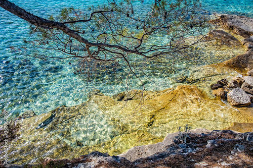 Aerial view of a slide turn from a drone on the view of calm turquoise sea water and rocks from molten lava. Pattern of sea surface and rocky shore.