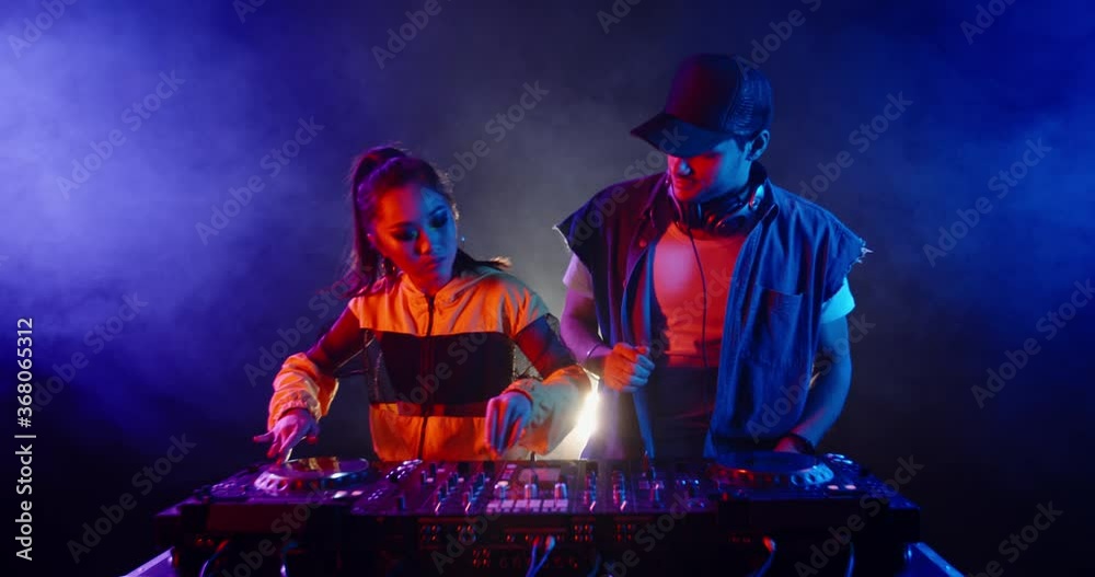 A dj couple is performing together in a nightclub, dancing at mixer controller, rocking the party up - nightlife concept 4k footage