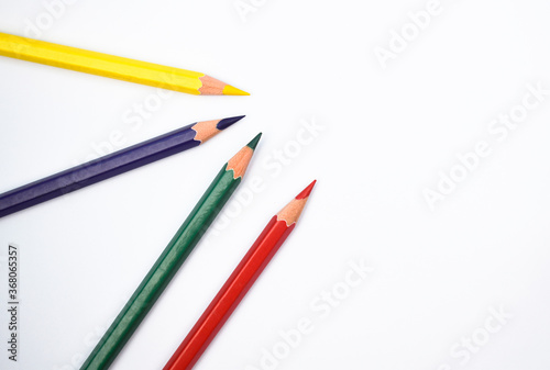 Red yellow blue and green colored wood pencil crayons placed on a paper