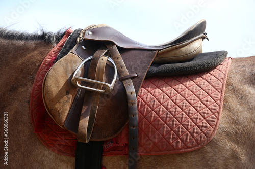 Photo of old leather saddle with stirrups