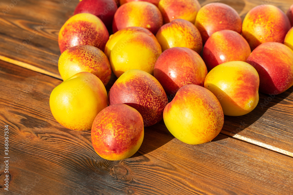 set of nectarines on wooden brown background in harsh sunlight