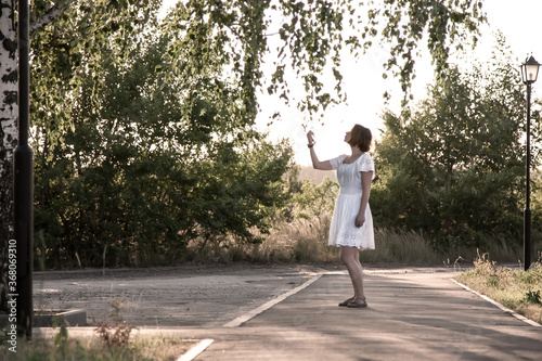 Girl in a white dress on the background of nature and a lamppost 