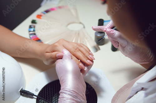 women s hands in pink gloves do manicure   