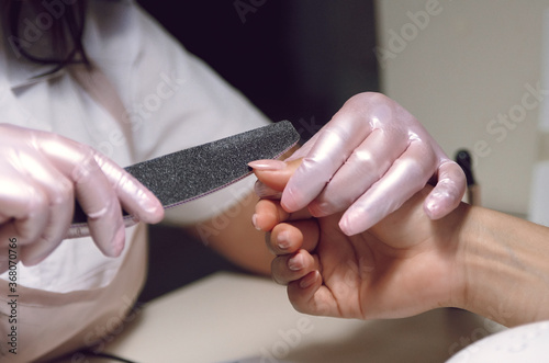  women's hands in pink gloves do manicure 