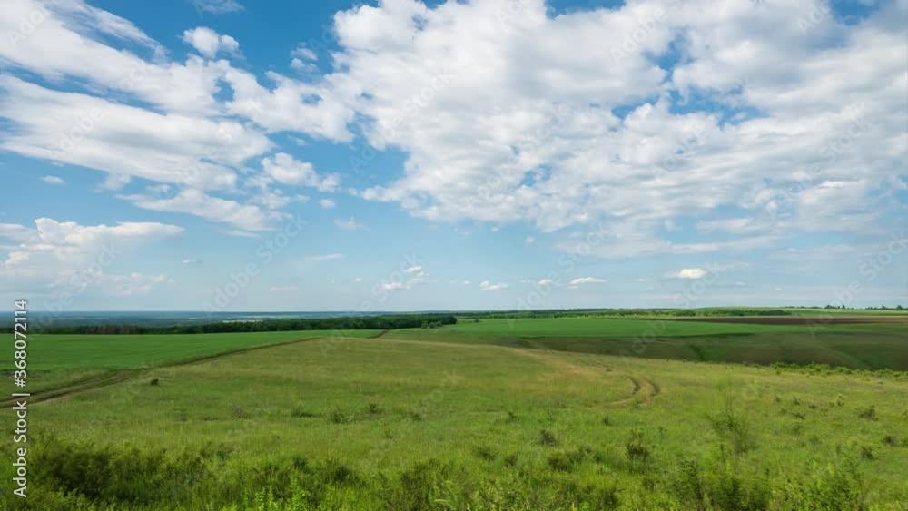 Timelapse. White clouds move quickly across the blue sky over a green fields Timelapse. White clouds move quickly across the blue sky over a green fields