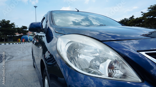 Close up front of blue car parking on the asphalt car park in motorway