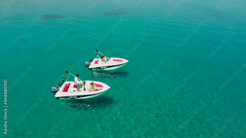 Aerial view of speedboats in turquoise crystal clear waters at sea, Pefkochori, Halkidiki, Greece, circular movement by drone Aerial view of speedboats in turquoise crystal clear waters at sea, Pefkochori, Halkidiki, Greece, circular movement by drone
