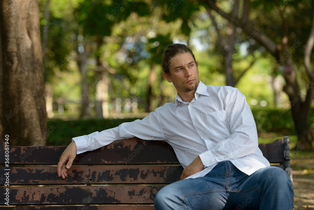 Handsome bearded businessman with long hair at the park Handsome bearded businessman with long hair at the park