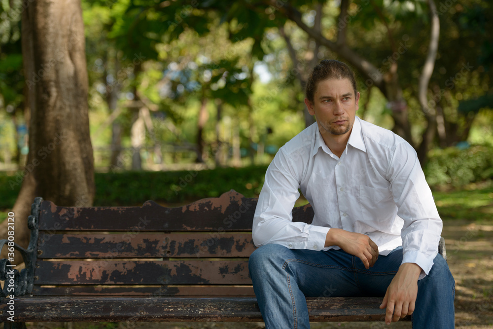 Handsome bearded businessman with long hair at the park