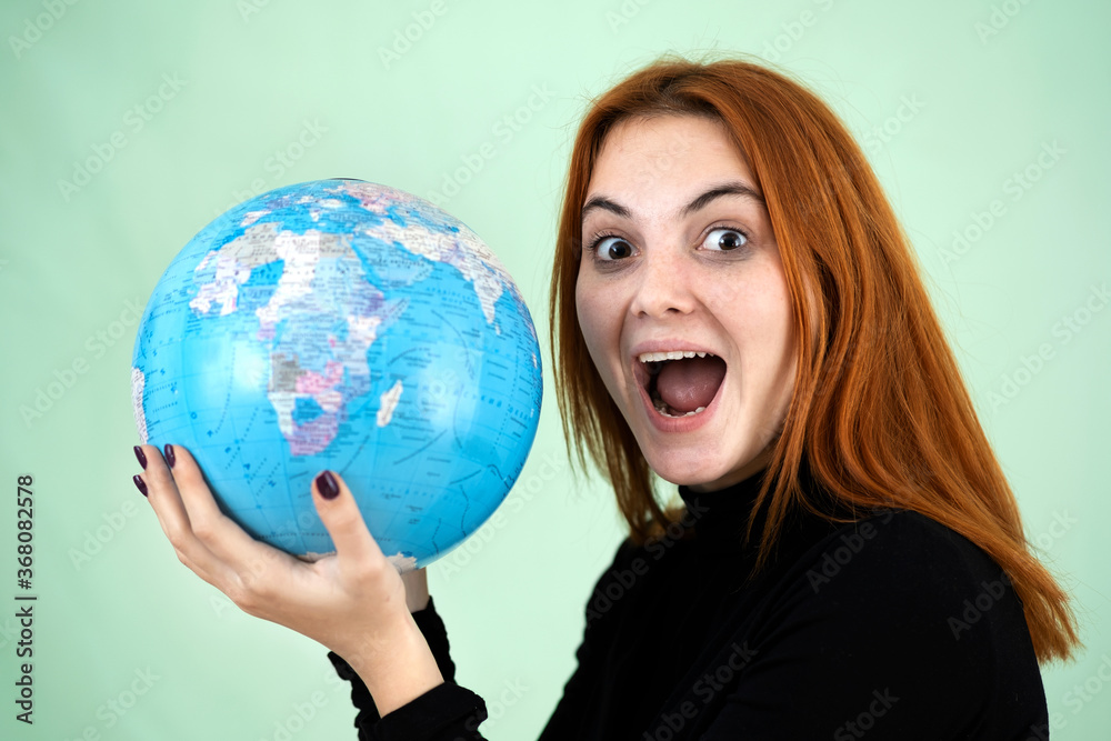 Portrait of a happy young woman holding geographic globe of the world in her hands. Travel destination and planet protection concept. Portrait of a happy young woman holding geographic globe of the world in her hands. Travel destination and planet protection concept.