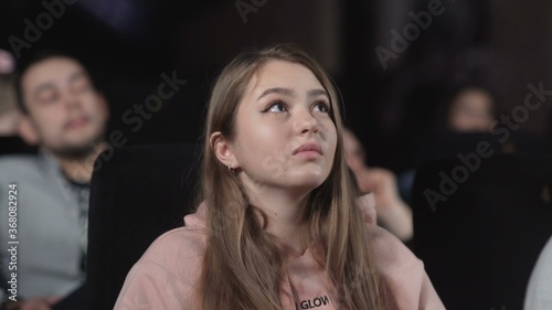 Foto Young woman is watching movie at cinema. emotion - interest