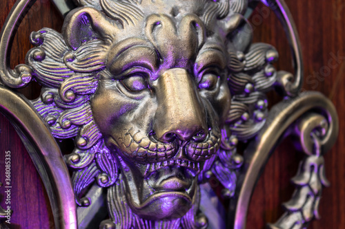 Close up to a golden Iron Lion shiled iluminated with violet light. Interior design, ornaments and welding concept