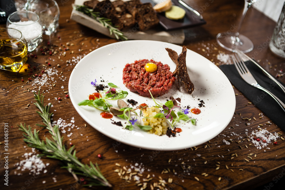 Steak tartare. Horseradish creme, black bread, baguette chips on white plate. Delicious healthy raw meat food closeup served on a table for lunch in modern cuisine gourmet restaurant. Steak tartare. Horseradish creme, black bread, baguette chips on white plate. Delicious healthy raw meat food closeup served on a table for lunch in modern cuisine gourmet restaurant.