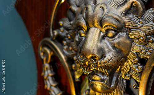 Close up to a golden Iron Lion shiled iluminated with yellow light and a septum piercing jewel . Interior design, ornaments, tattoo and piercing concept